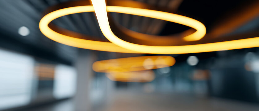 Abstract blurred image of modern circular yellow ceiling lights in a spacious industrial interior with dark ceiling and open space