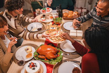 Joyful holiday gathering with friends sharing festive cookies, enjoying roast turkey, and sipping...