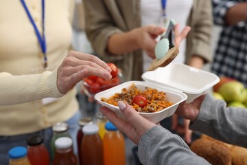 Volunteers giving food to homeless people in shelter, closeup