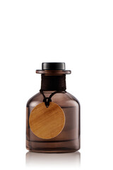 A brown glass bottle with a cork lid sits upright on a smooth white surface. The bottle has a round wooden tag attached to its neck. This setup gives a clean and uncluttered look.
