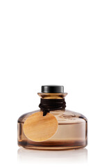 A bottle of perfume sits on a plain white background. The bottle is round with a black cap and has a wooden tag tied around its neck.