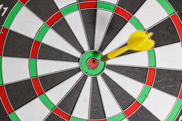Yellow Dart arrow hitting in the target of classic dartboard. Selective focus. the concept of focus and precision. goals and target. High quality photo