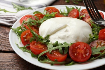 Delicious burrata cheese with arugula and tomatoes on wooden table, closeup