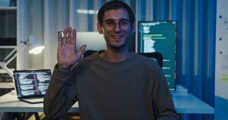 Adult male freelance programmer work late speak in online meeting video conference and looking at camera in tech office night. Artificial intelligence, robotics, user interface, machine learning.