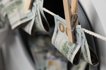 Banknotes hanging on clothesline near washing machine, closeup. Space for text