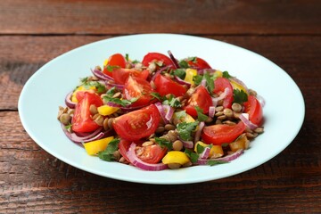 Delicious salad with lentils and vegetables on wooden table, closeup