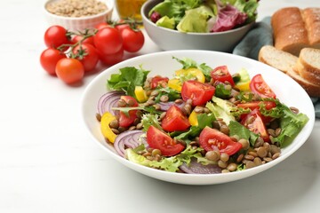 Delicious salad with lentils and vegetables served on white table, closeup