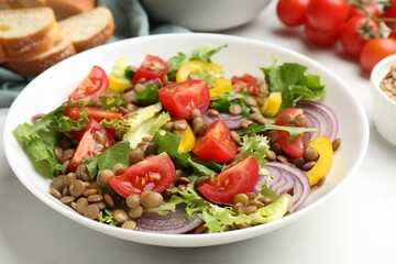 Delicious salad with lentils and vegetables served on white table, closeup