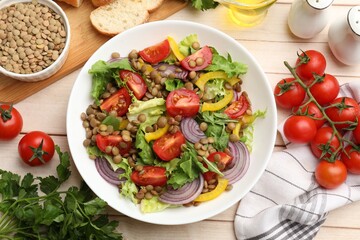 Delicious lentil salad and ingredients on light wooden table, flat lay