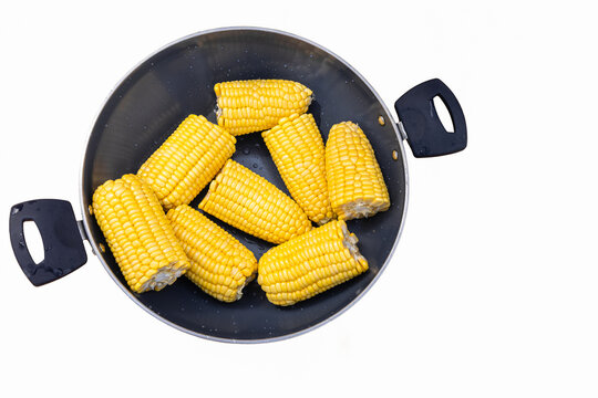 Bright yellow boiled corn cobs halves in a pot, viewed from directly above on white background - Powered by Adobe