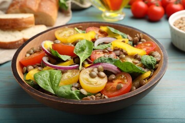 Tasty salad with lentils and vegetables on light blue wooden table, closeup
