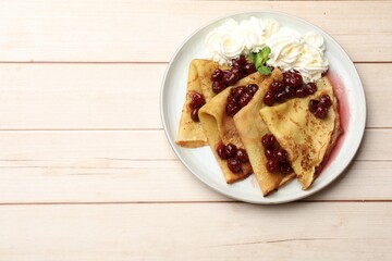 Tasty crepes with cherries, whipped cream and mint on white wooden table, top view. Space for text