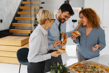 Coworkers enjoying a casual break in a modern office while sharing pizza.
