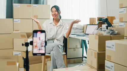 Youth Asia lady owner small business online shop sit front of phone look at camera live streaming...