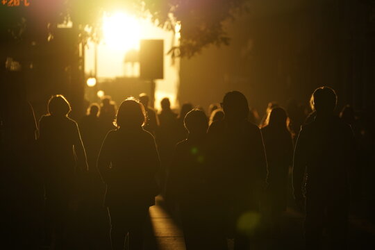 Personas caminando en la luz de un atardecer en la calle de la ciudad