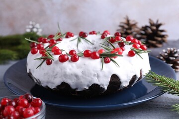 Tasty Christmas cake with cranberries, rosemary and festive decor on gray wooden table, closeup