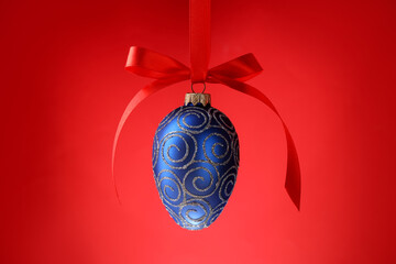One Christmas bauble with bow hanging against red background, closeup