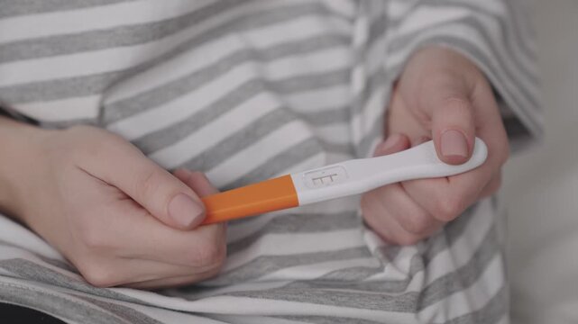 a girl holding a pregnancy test in her hands, the result is two strips with a delay in the menstrual cycle, a pregnant woman, the conception of a child in the first trimester, a new life for baby.