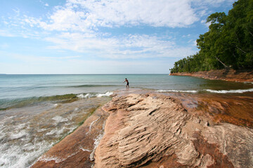 Lone person wading into the calm water of Lake Superior in Michigan