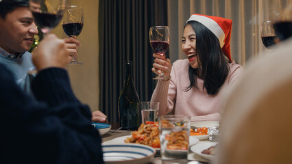 Group of Asia colleague friends gathering New year holidays party together. Happy man host toast glass of wine with guest start eat christmas dinner at home in evening, celebration and people concept.