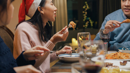 Group of Asia colleague gathering New year holidays party together. Group of happy friends enjoy eat good food over Christmas table thanksgiving dinner at home at night, celebrate and people concept.