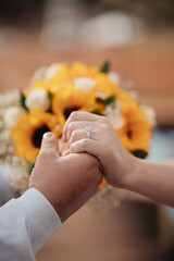 Man holding his partner's hand with wedding ring