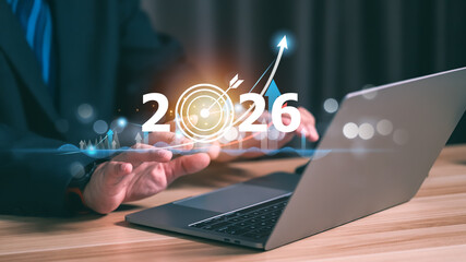 Businessman analyzing data on laptop with 2026 target board interface. Concept of global business goals, corporate strategy, financial investment growth, and new year development.
