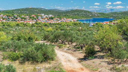 Croatian coastal landscape with green hills, blue water and a small town on the seashore, view from...