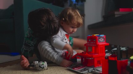 Older child reaching toward toddler during play with toy fire station creating authentic sibling tension as younger child pulls back showing brief quarrel mixed with curiosity and interaction - Powered by Adobe