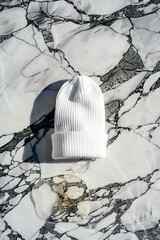 Plain white knitted headwear rests centrally on a surface of dramatic black and white veined stone