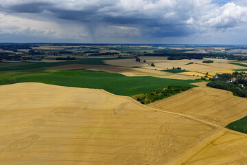 Naklejka premium Aerial drone view of rural villages and agricultural fields near Opole and Nysa in Poland, showing geometric farmland patterns, scattered houses, winding country roads and green meadows in daylight