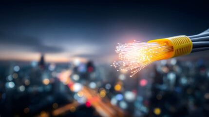 Fiber optic cable glowing with light strands over blurred cityscape at dusk conveying high speed connectivity and innovation
