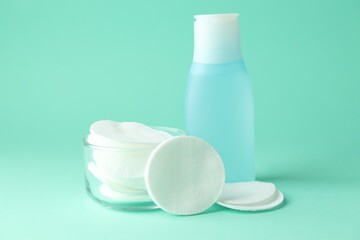 Clean cotton pads and micellar water on turquoise background. Space for text