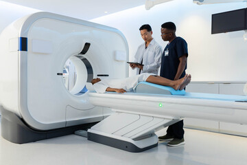 CT scanner gantry rotating while motorized exam table sliding into bright radiology suite
