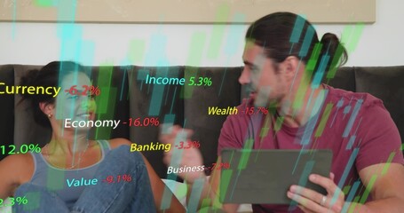 Gesturing couple holding tablet and laughing on dark leather sofa at home, showing finance charts
