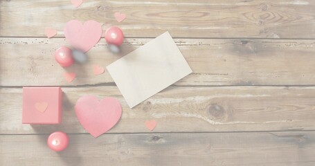 Displaying Valentine cluster on rustic wood table, with blank white card, pink hearts and gift box