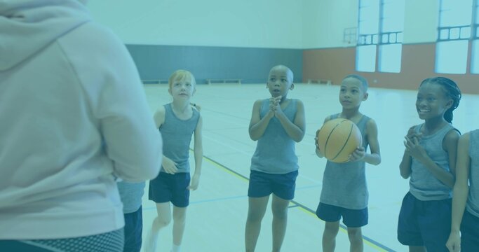 Lining up children listening to coach giving instruction on gym court with basketball, hoodie - Powered by Adobe