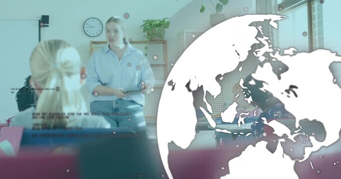 Teaching woman in blue shirt and jeans speaking at front of class, with whiteboard, globe overlay