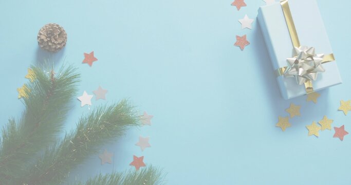 Naklejki Sitting light-blue-gift gold-ribbon silver-bow on pale-blue surface firsprig cone stars, copy space