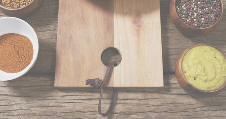 Showing light cutting board with round hole and leather strap on rustic tabletop, with spice bowls