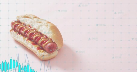Displaying single hot dog resting on pastel pink grid tabletop showing mustard ketchup, teal charts