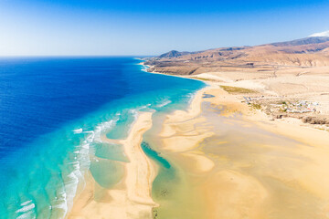 Playa de Sotavento is a famous beach on the southeastern coast of Fuerteventura, known for its long stretches of golden sand, turquoise water, and consistent winds