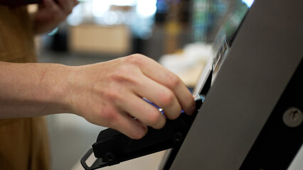Close-up of a customer inserting a credit card into a pos terminal and typing the pin code, completing a purchase transaction in a retail store