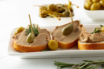 Sandwiches with pate on a white wooden table.