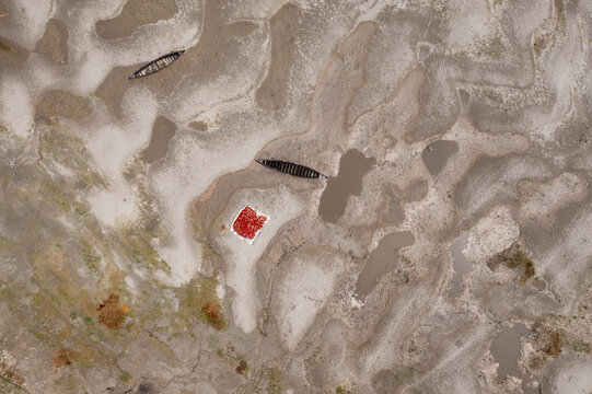 Aerial view of boats adrift on the sandy, patterned earth, with a spot of vibrant red, creating a striking contrast in the landscape, Bogura, Rajshahi Division, Bangladesh.