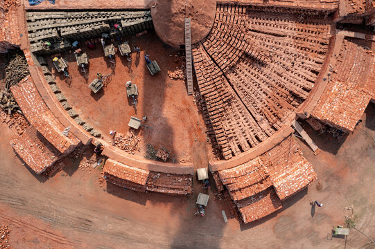 Aerial view of a brick kiln with its distinctive circular design, showcasing the earthy tones and structured layout of the brick-making process, Bogura, Rajshahi Division, Bangladesh.