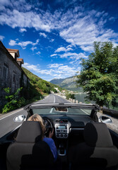 Young woman driving convertible along scenic ocean coast and mountain road at sunset, carefree...