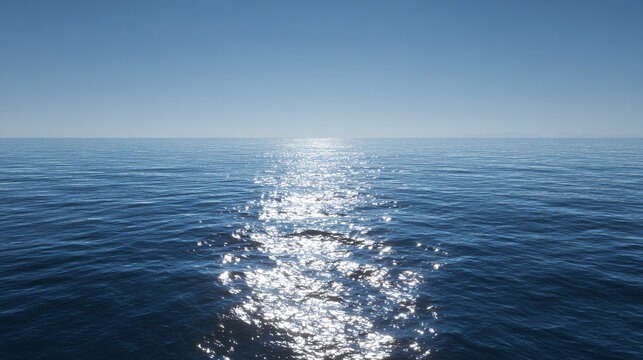 The sun's reflection shimmers on the ocean surface under a clear blue sky, creating a breathtaking seascape