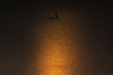 Tekstura lodu z naturalnymi wzorami rozświetlona ciepłym światłem zachodzącego słońca. Złota poświata podkreśla delikatne pęknięcia i struktury, tworząc abstrakcyjną i nastrojową zimową scenerię.