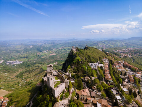Aerial view of the ancient fortress clinging to the rugged mountain peak, with its weathered stone walls contrasting against the vibrant green landscape, San Marino, San Marino.